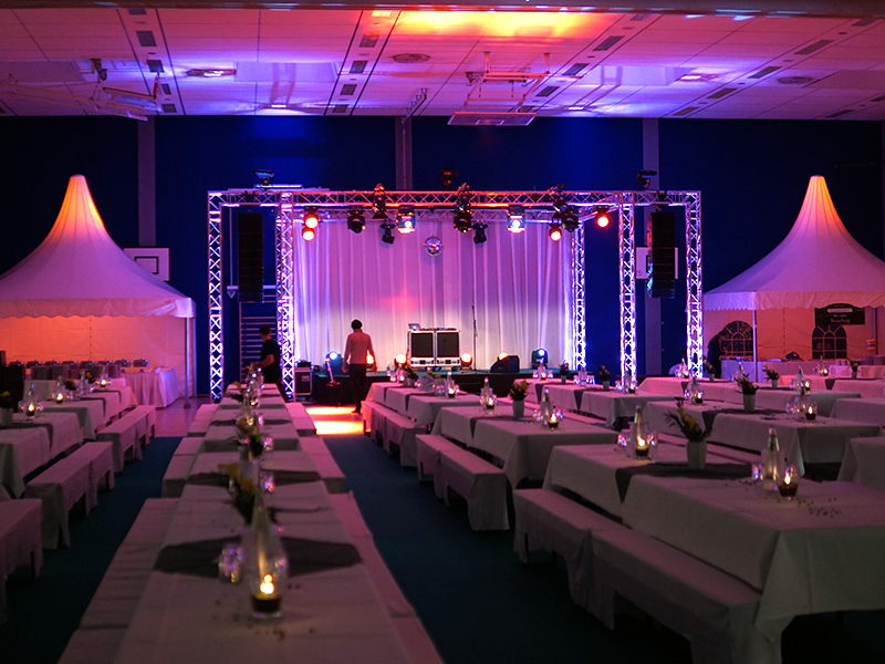 Saal mit gedeckten Tischen und Bühne