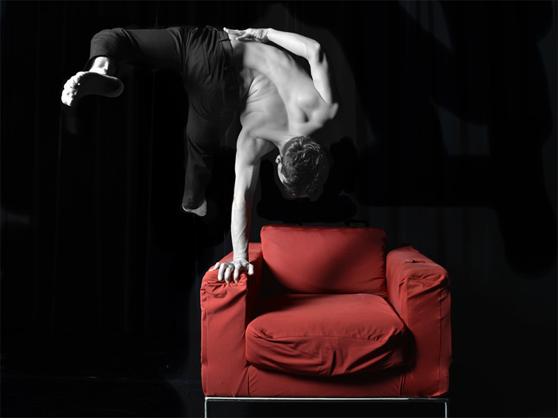 einhändiger Handstand auf rotem Sessel
